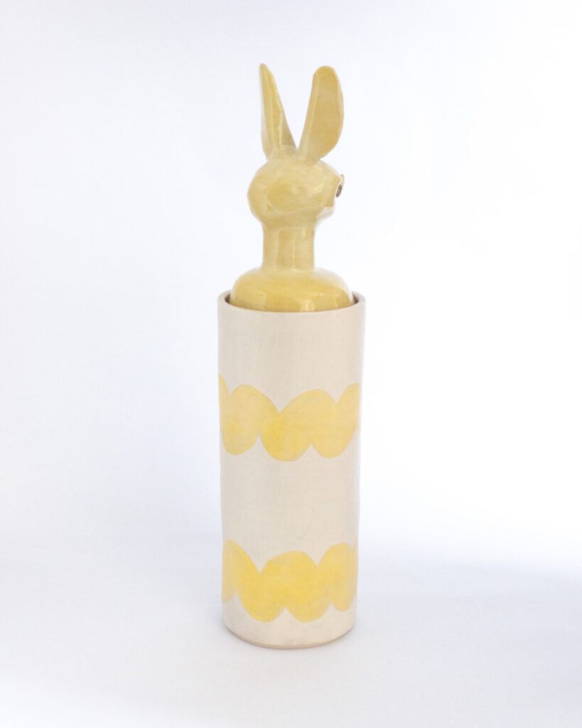 Cylindrical ceramic jar with a lid in the form of a yellow bat head, rear view