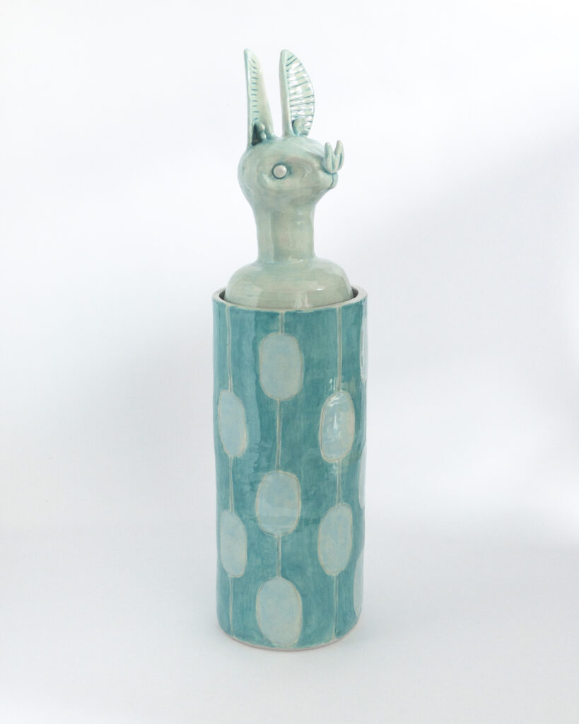 Cylindrical ceramic jar with a lid in the form of a blue bat head, side view