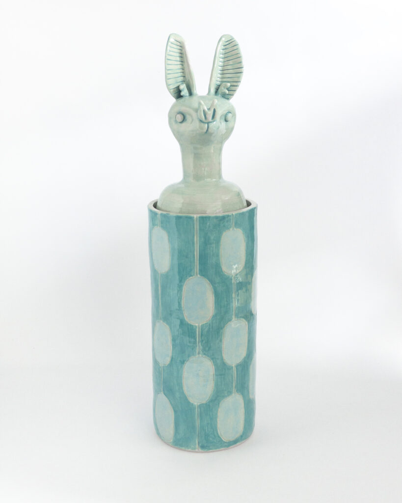 Cylindrical ceramic jar with a lid in the form of a blue bat head, front view