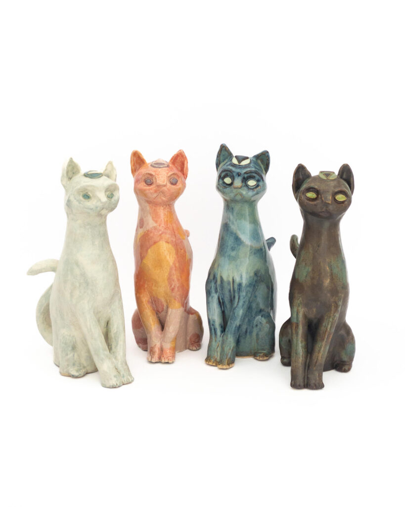 4 ceramic cats representing the elements and glazed accordingly: brown and green for earth, cloudy white for air, swirls of pink and orange for fire and drippy blues and greens for water