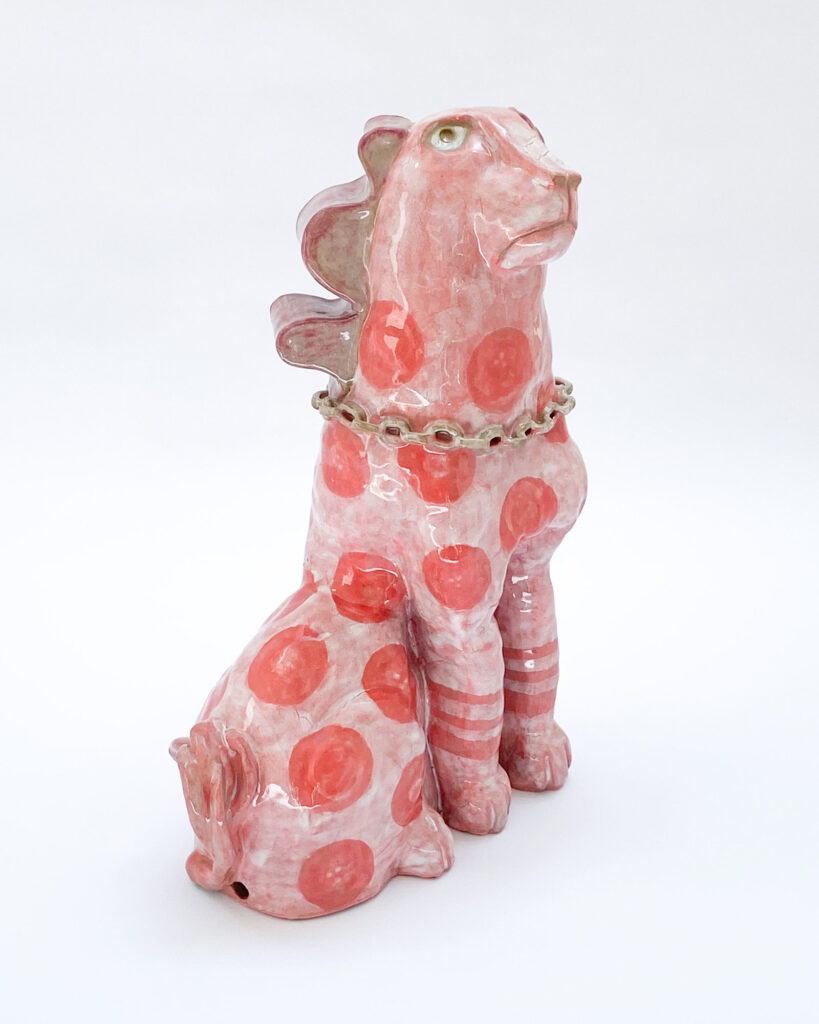 Ceramic sculpture of a quirky dog with pink glaze and darker pink spots, side view