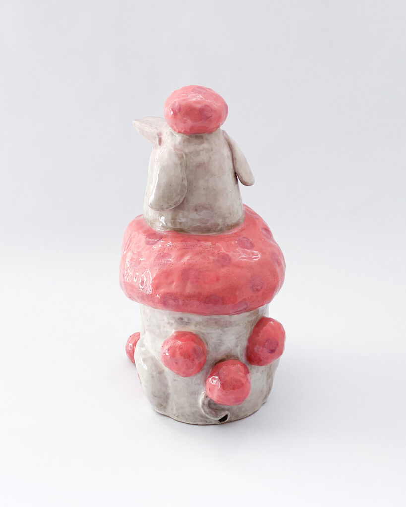 Ceramic poodle with pink fur and white skin, with Sissy written across his chest in blue letters, rear view
