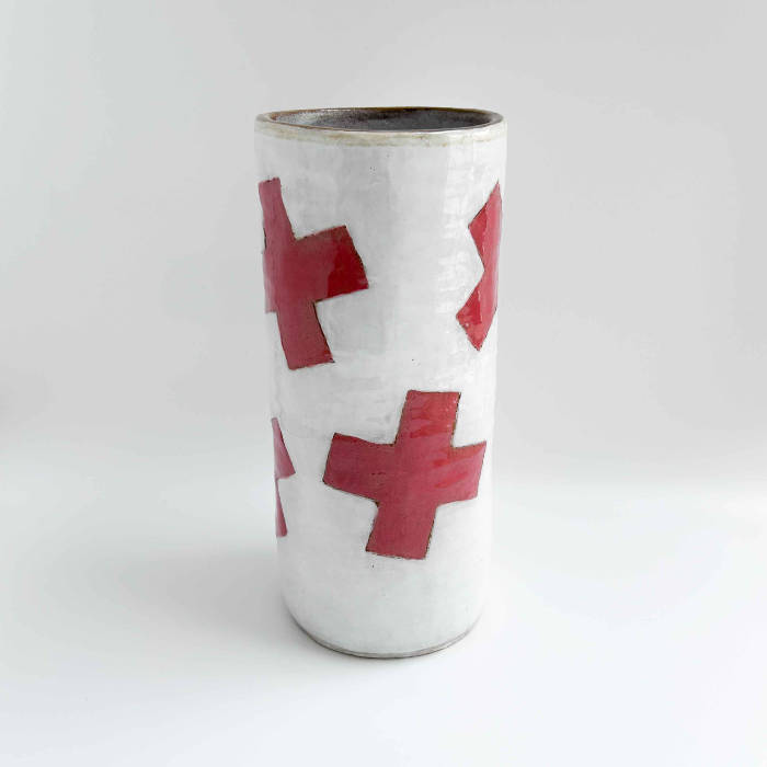Ceramic cylindrical jar with white glaze and graphic red plus symbols scattered over the surface