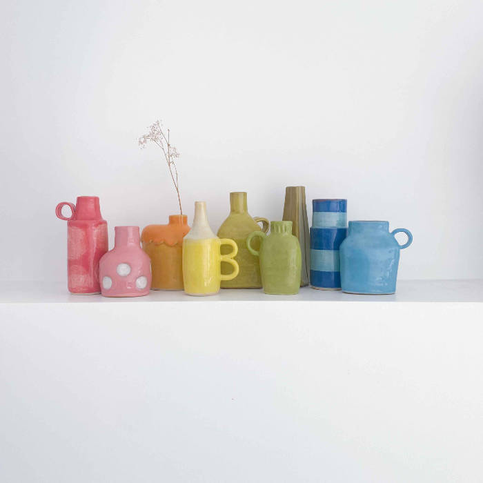 A group of ceramic bud vases, all unique and different, in rainbow colours