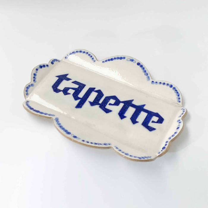 Ceramic scalloped tray in white glaze with "Tapette" in blue blackletter written across it