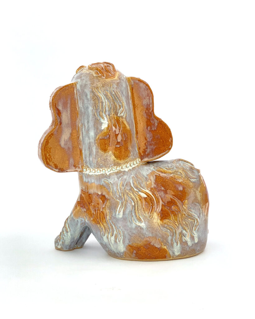 Ceramic spaniel in brown and white melty glazes, shown from behind
